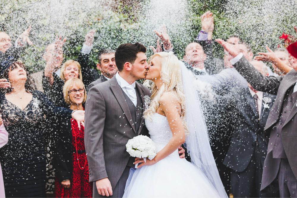 bride and groom kissing under confetti